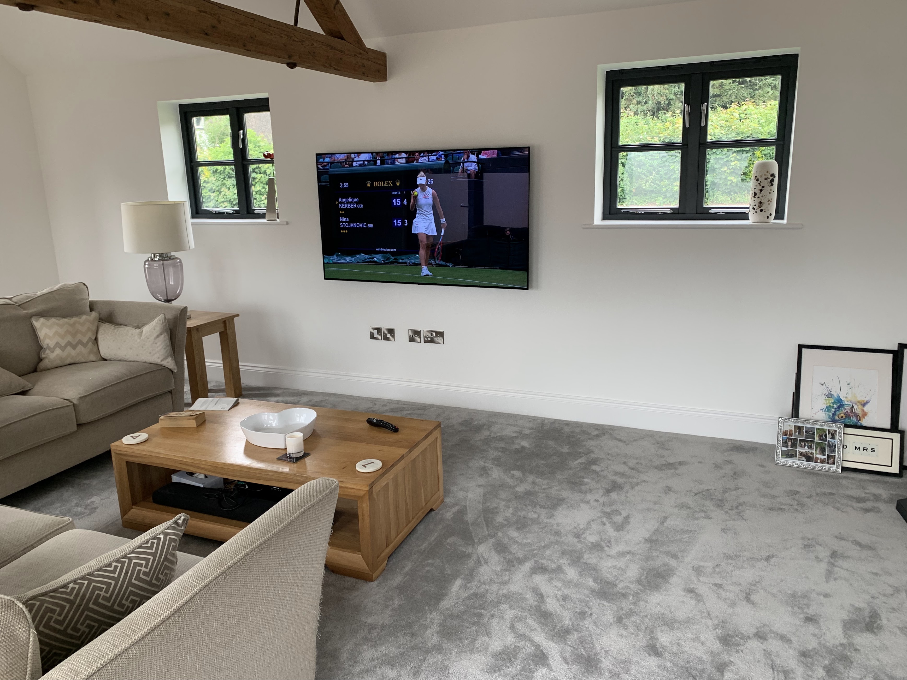 Large TV wall mounted in barn conversion with exposed beams